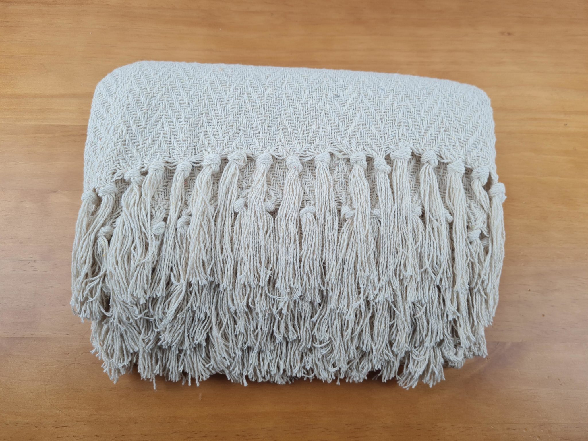Manta confeccionada em 100% algodão na cor cru, detalhes em tassel (franjas)