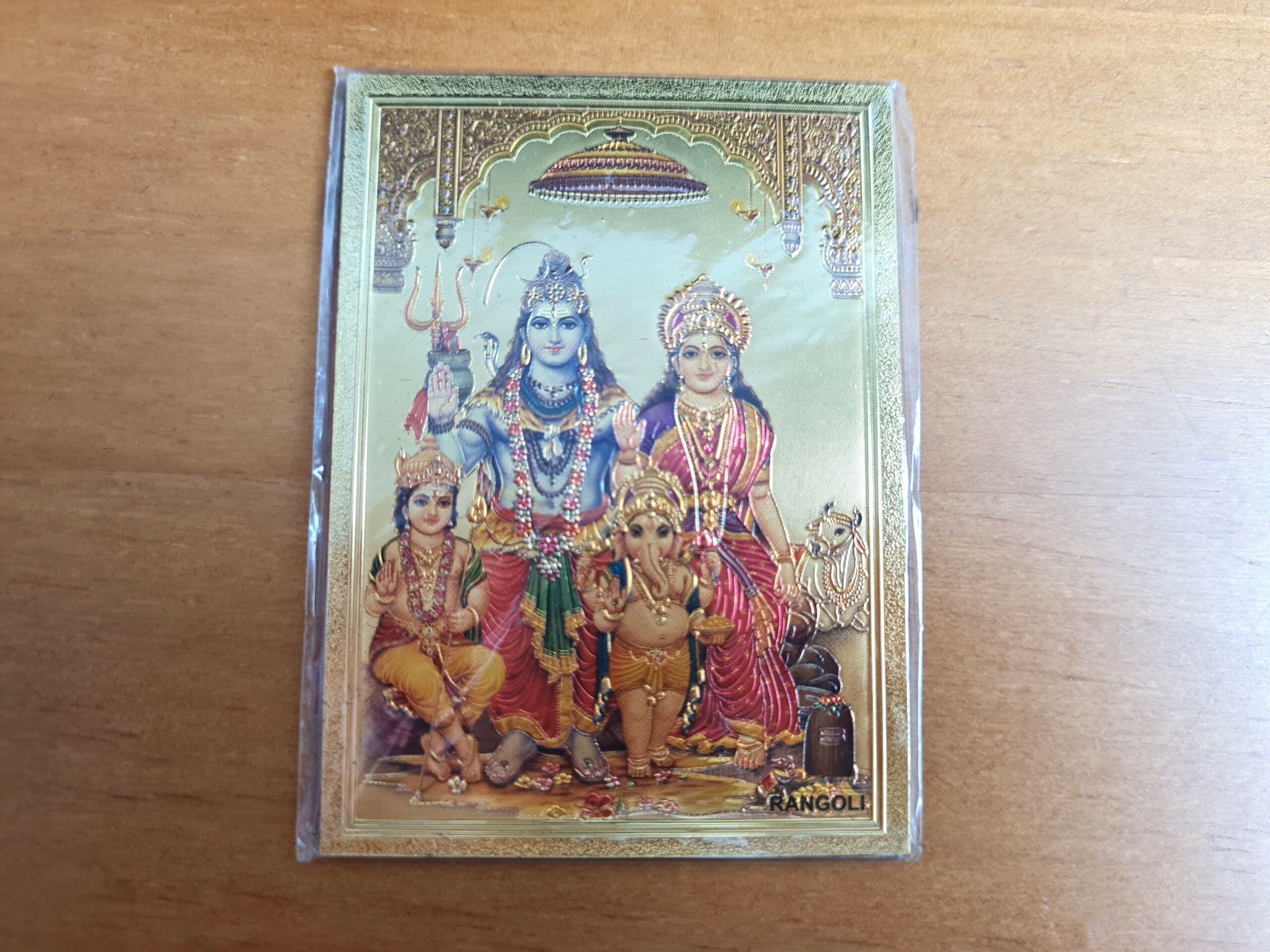 Ímã de geladeira indiano com estampa de Shiva e família, revestido com lâmina dourada e textura brilhante. Lindo para decorar a sua cozinha!