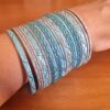 Conjunto de 24 pulseiras indianas de metal com brilhos azul claro e prateado