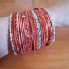Conjunto de pulseiras indianas com brilhos. Possui 7cm de diâmetro, cor laranja com detalhes prateados